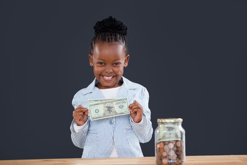 Portrait of cheerful businesswoman with coins jar showing paper currency