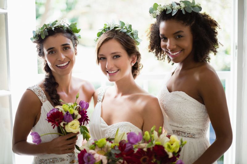 Bride and bridesmaids standing with bouquet at home