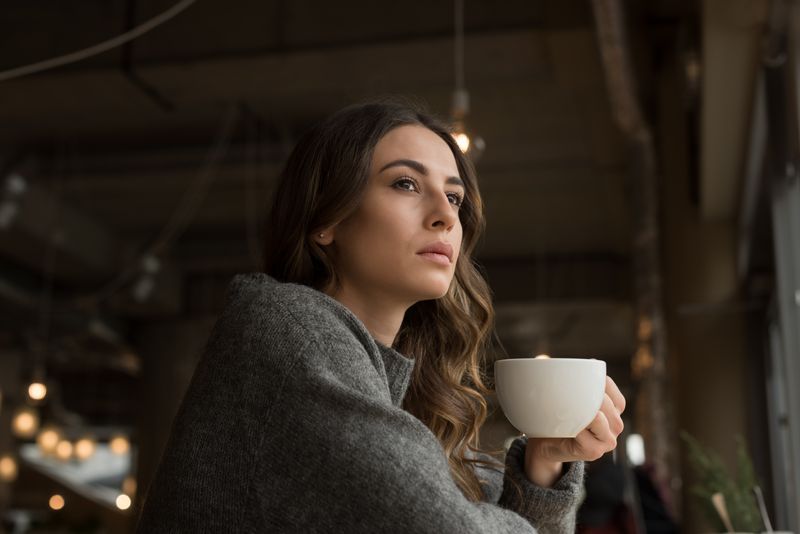 Contemplated woman having coffee in cafe