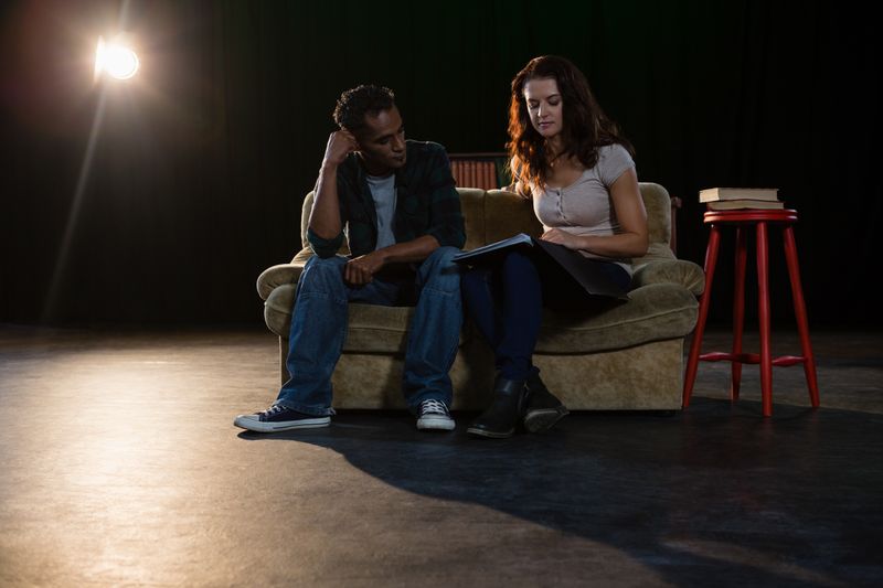 Actors reading their scripts on stage