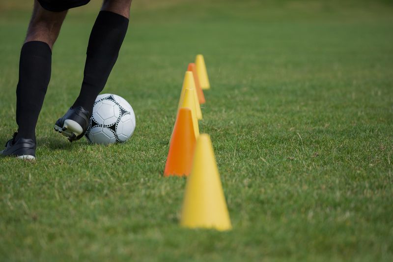 Soccer player dribbling through cones