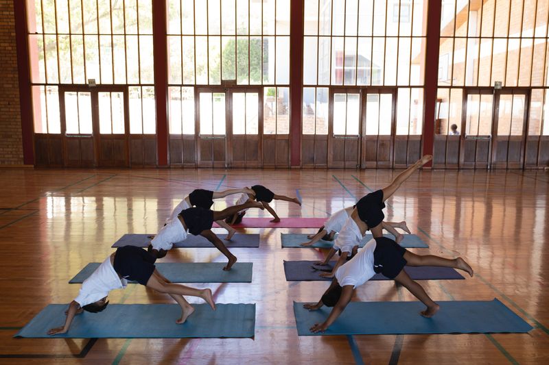 Schoolkids doing yoga on a yoga mat in school