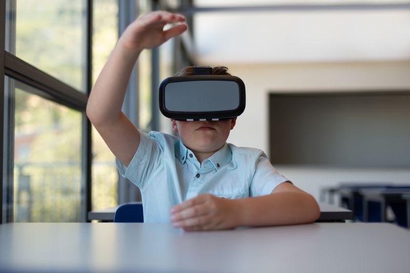 Schoolboy using virtual reality headset in a classroom