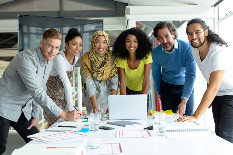 Front view of diverse business people looking at camera while working together at conference room in a modern office