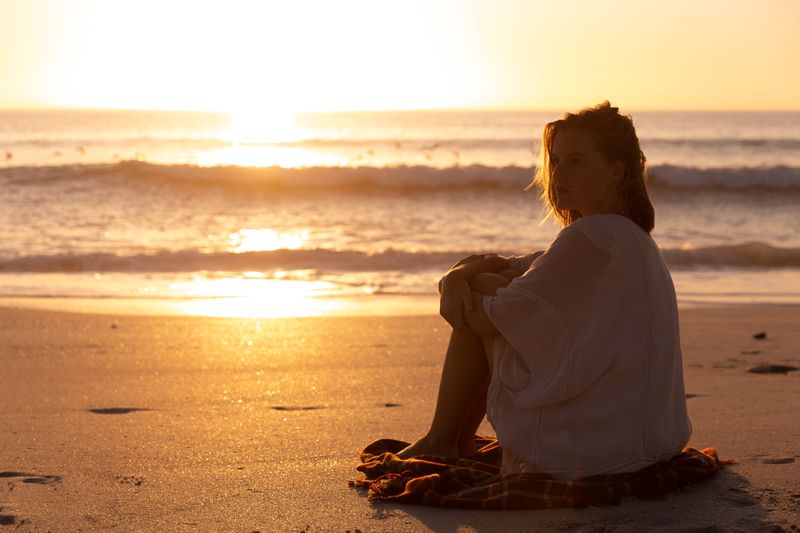 Beautiful woman sitting on the beach during sunset