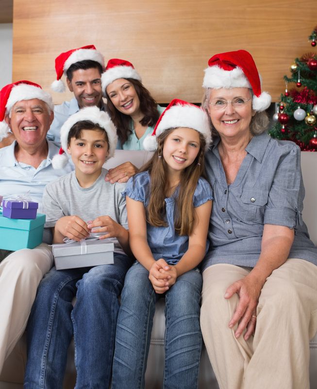 Extended family in Christmas hats with gift boxes in living room