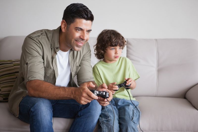 Father and son playing video games in living room