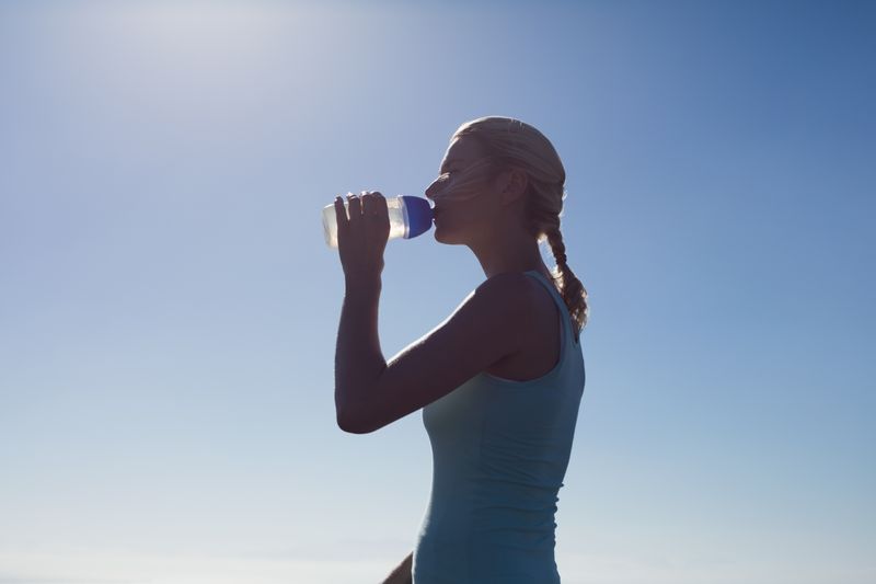 Fit woman drinking from water bottle