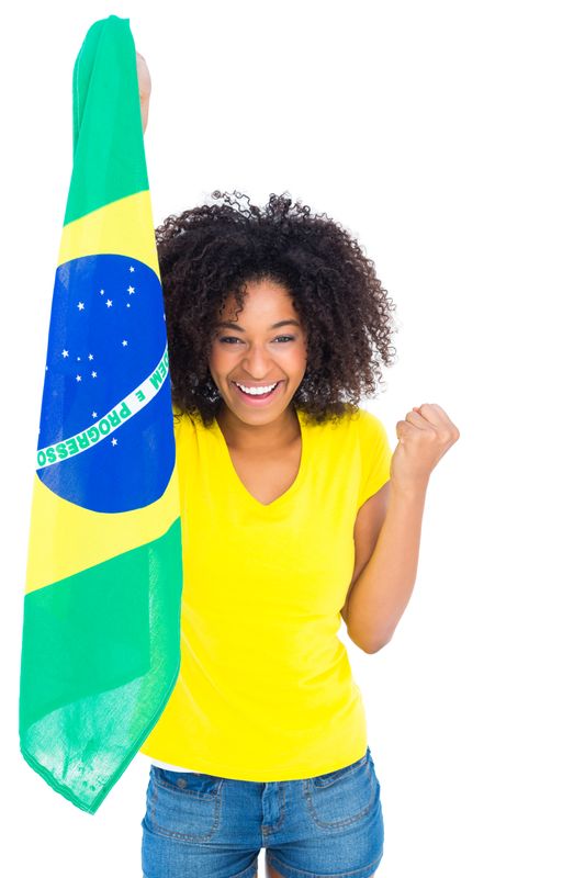 Pretty girl in yellow tshirt holding brazilian flag cheering at camera
