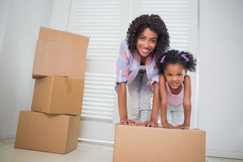 Cute daughter unpacking moving boxes with her mother