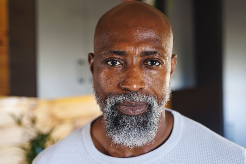 Close-up portrait of bald and bearded african american senior man in log cabin. Unaltered, retirement, lifestyle, vacation, solitude, holiday, confident and leisure concept.