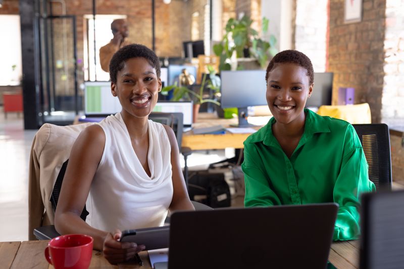 Portrait of happy african american colleagues using tablet in creative office. Business, technology and teamwork, unaltered.