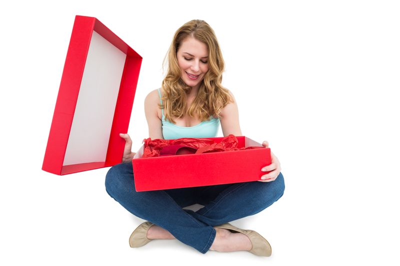 Pretty woman opening a gift smiling at it