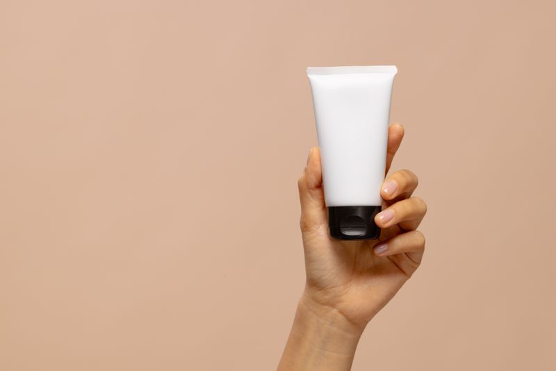 Hand of asian woman holding tube of beauty cream with copy space