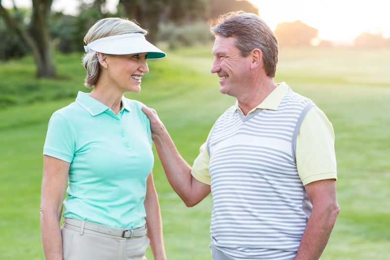 Golfing couple smiling at camera on the putting green 