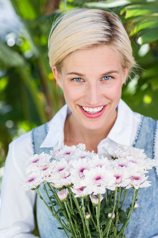 Pretty blonde woman holding bunch of flowers