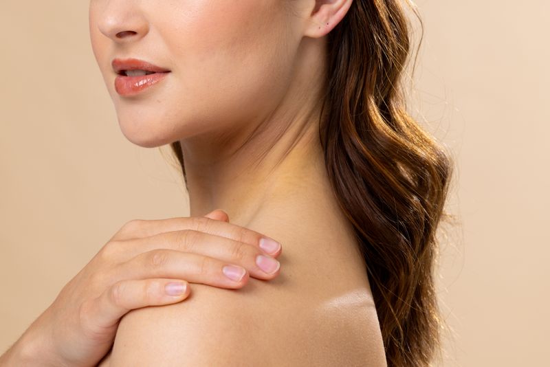 Caucasian woman with brown hair wearing natural makeup on beige background