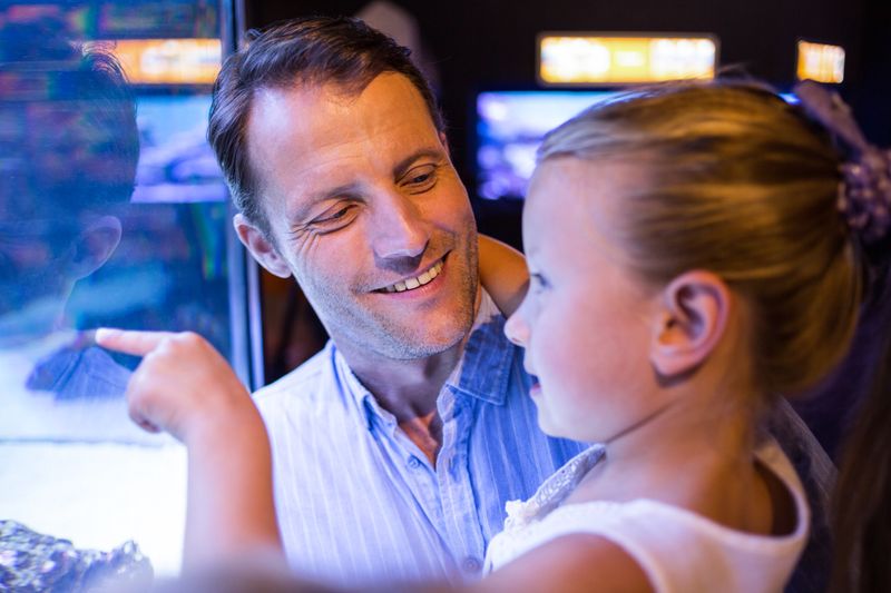 Daughter looking and father looking at fish in tank 