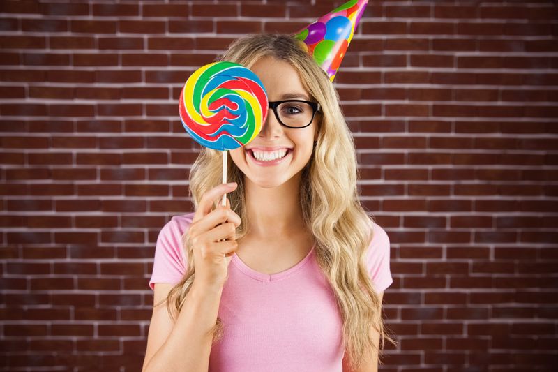 Portrait of a hipster hiding herself behind a lollipop