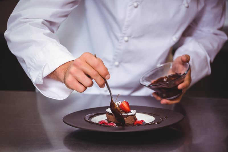 Chef putting chocolate sauce on a dessert