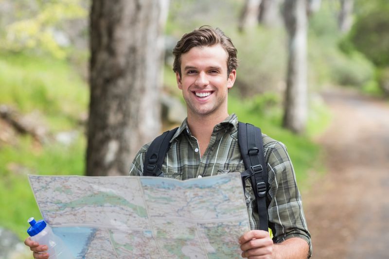 Happy young man with map on footpath