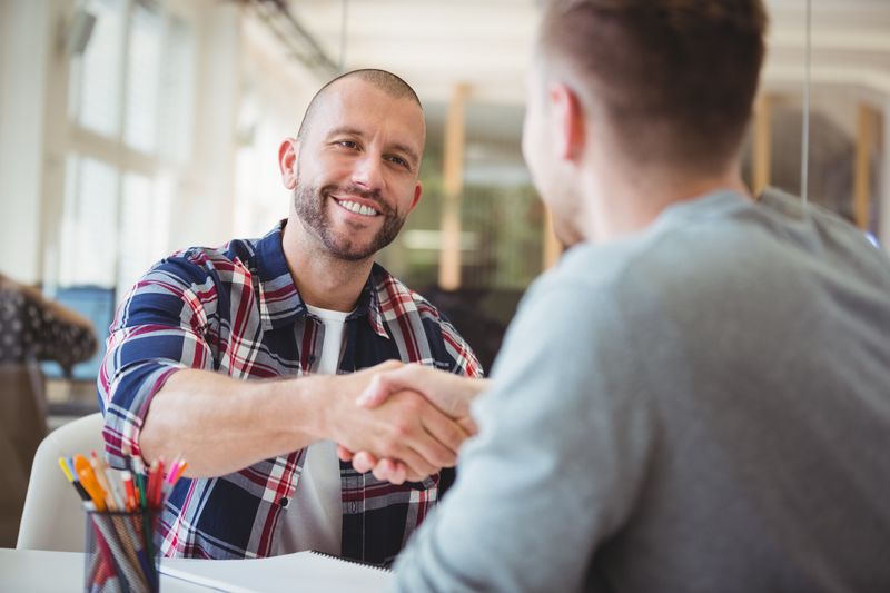 Young business people shaking hands in creative office