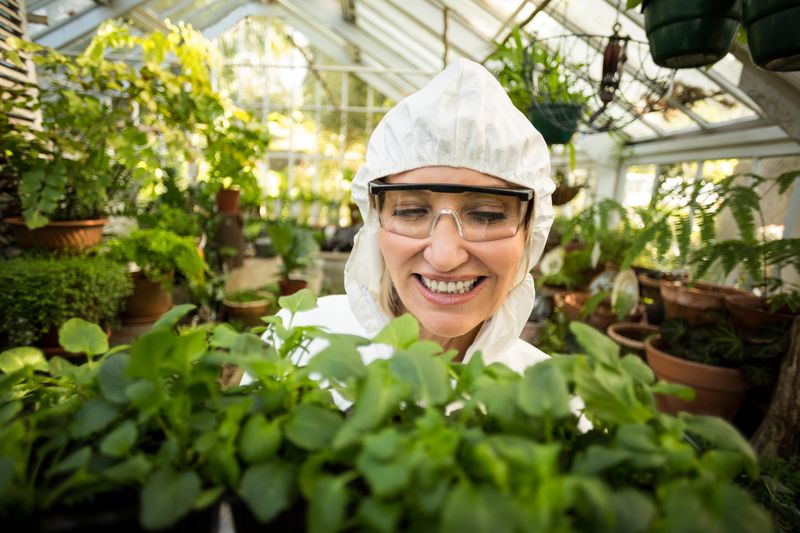 Female scientist smiling while holding plants