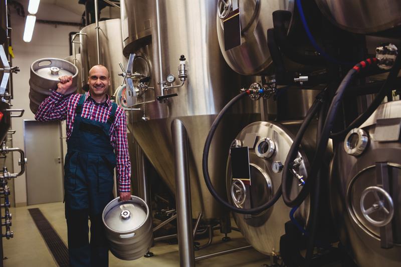 Portrait of brewery worker carrying kegs