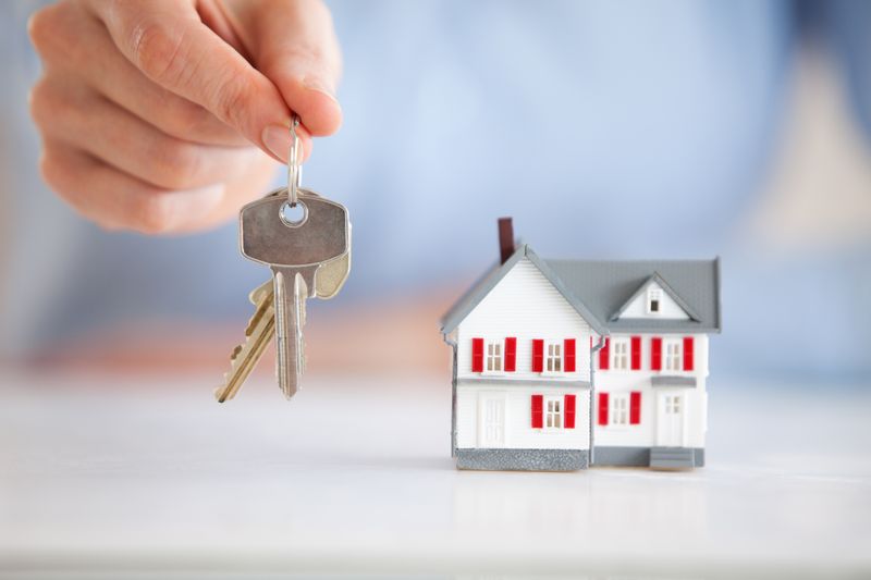 Woman holding keys next to a model house