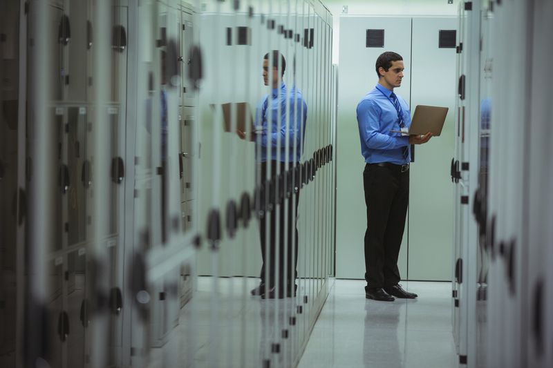 Technician using laptop while analyzing server