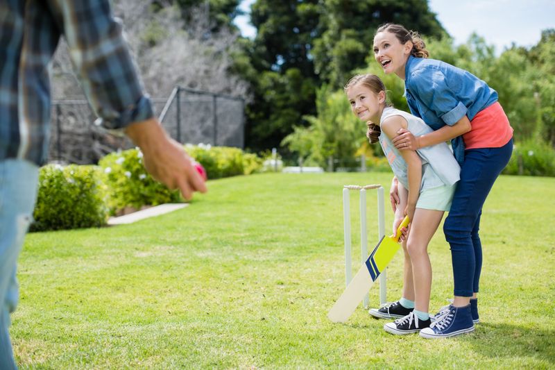 Family playing cricket in park