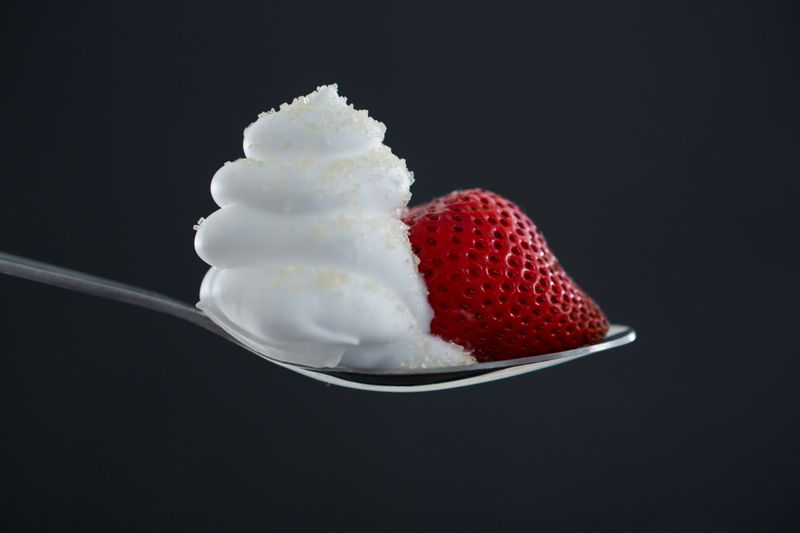 Close-up of fresh strawberry with cream in spoon