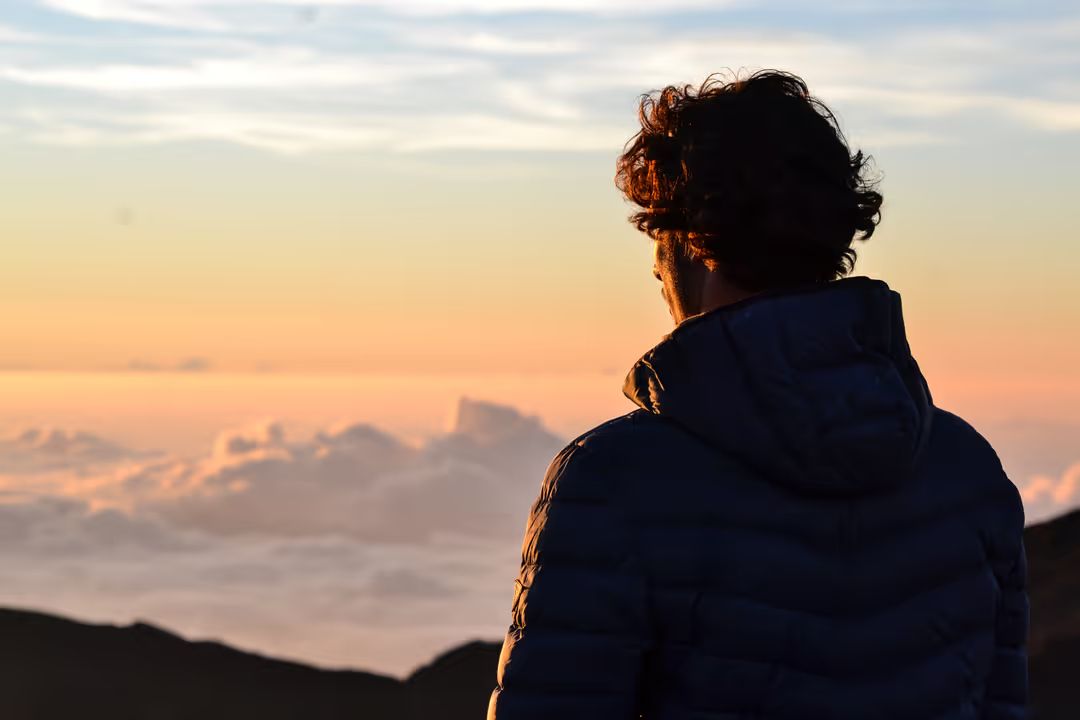 Image of a man looking out from a mountain top at sunrise - Meaning and use of hero image in web design - Image
