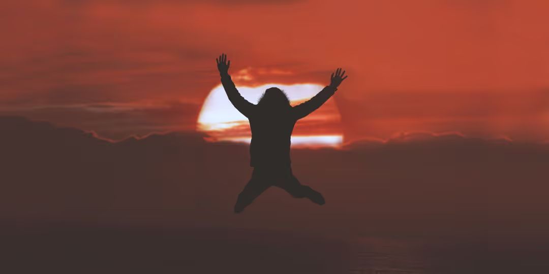 Silhouette of a person jumping in front of a red sunset - Must-know design tips for using images on websites - Image