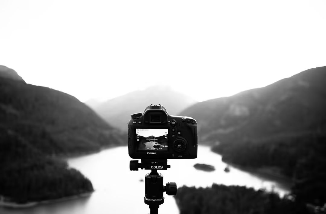 Black and white image of a camera on a tripod with mountains in the background - The benefits of high-quality video in your marketing content - Image