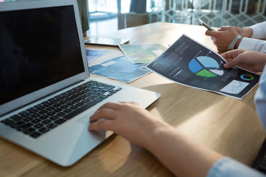 Executive working on project while using laptop at desk - 15 essential graphic design tips from the experts for industry beginners - Image