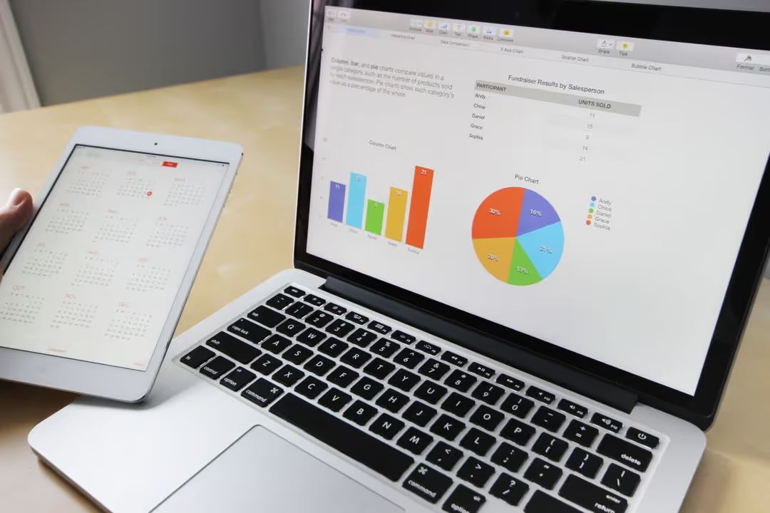 Image of a person holding an iPad with the calendar app visible while there are statistics on an Mac laptop notes app in the background - Simple but powerful tactics for crafting compelling ad copies that drive sales - Image