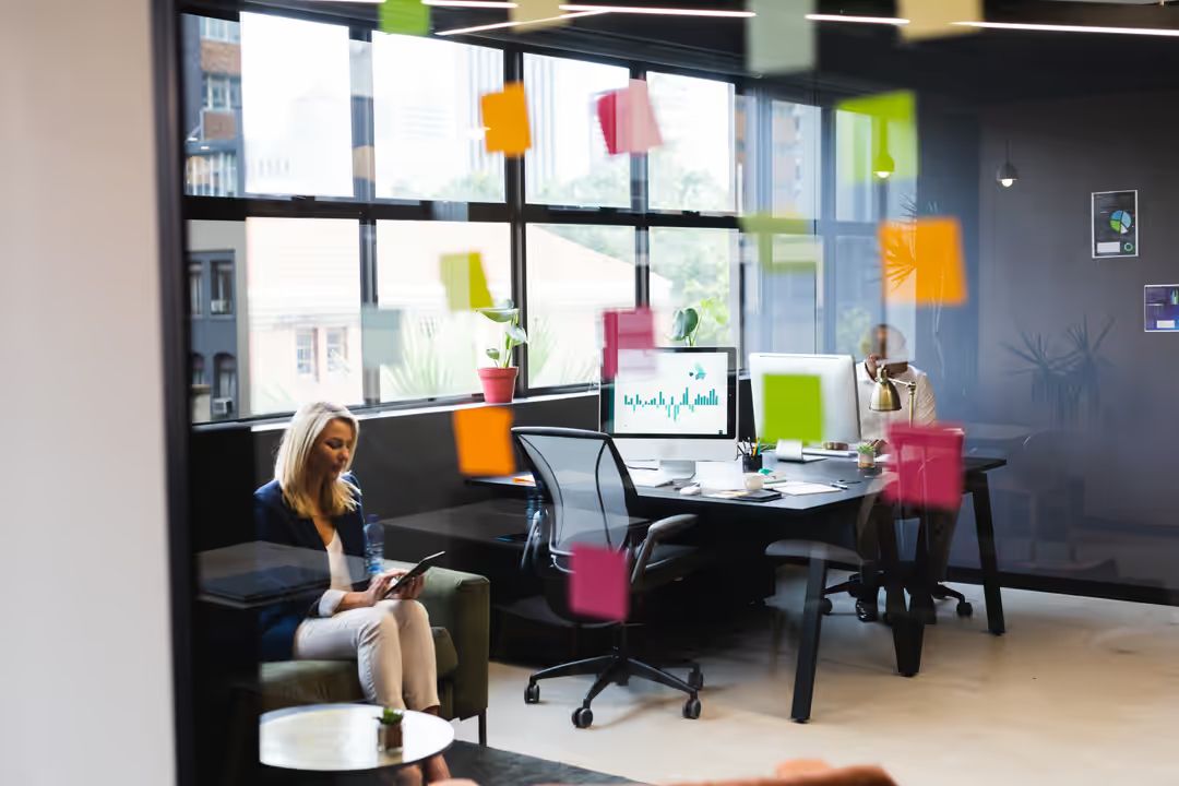 Image of a business woman sitting on a couch using her phone at an office - A selection of great images for virtual Zoom backgrounds from the PikWizard team - Image