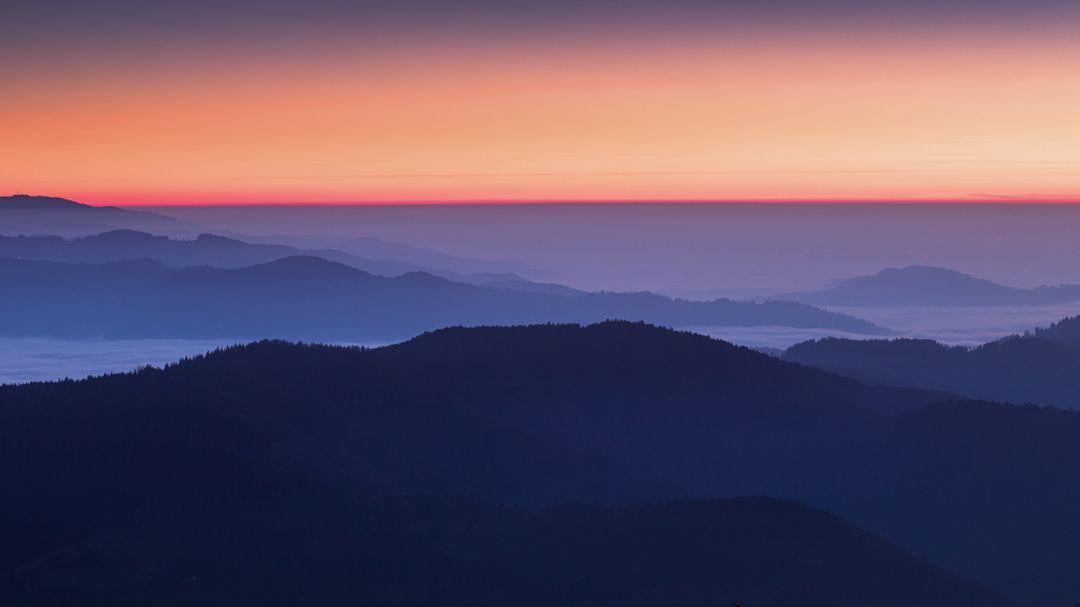 Image of a blue, purple and pink sunset behind a mountain landscape - How to create the best modern color scheme for your website - Image
