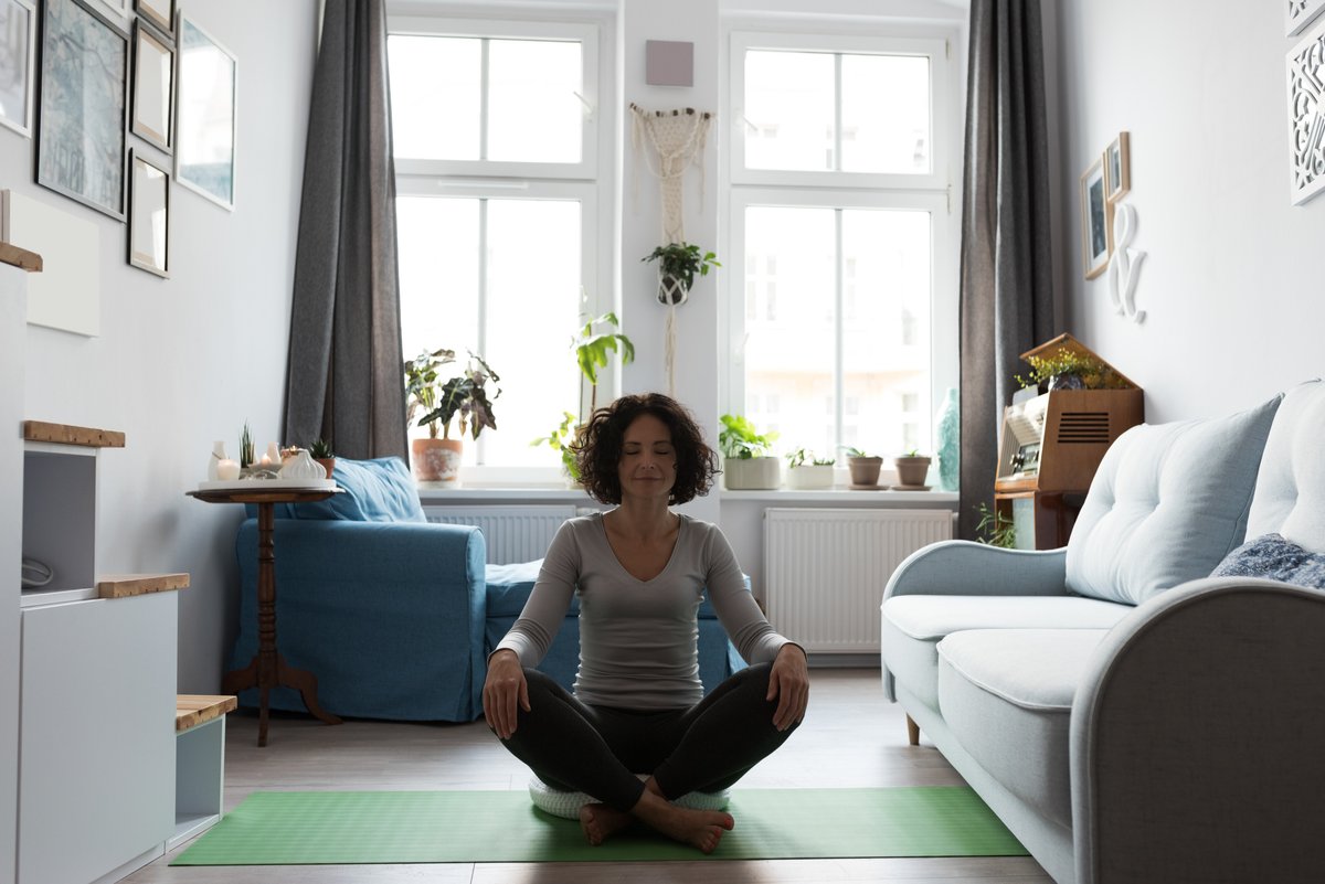 Photo of woman meditating in living room with open windows - What it takes to start a fitness blog - Image