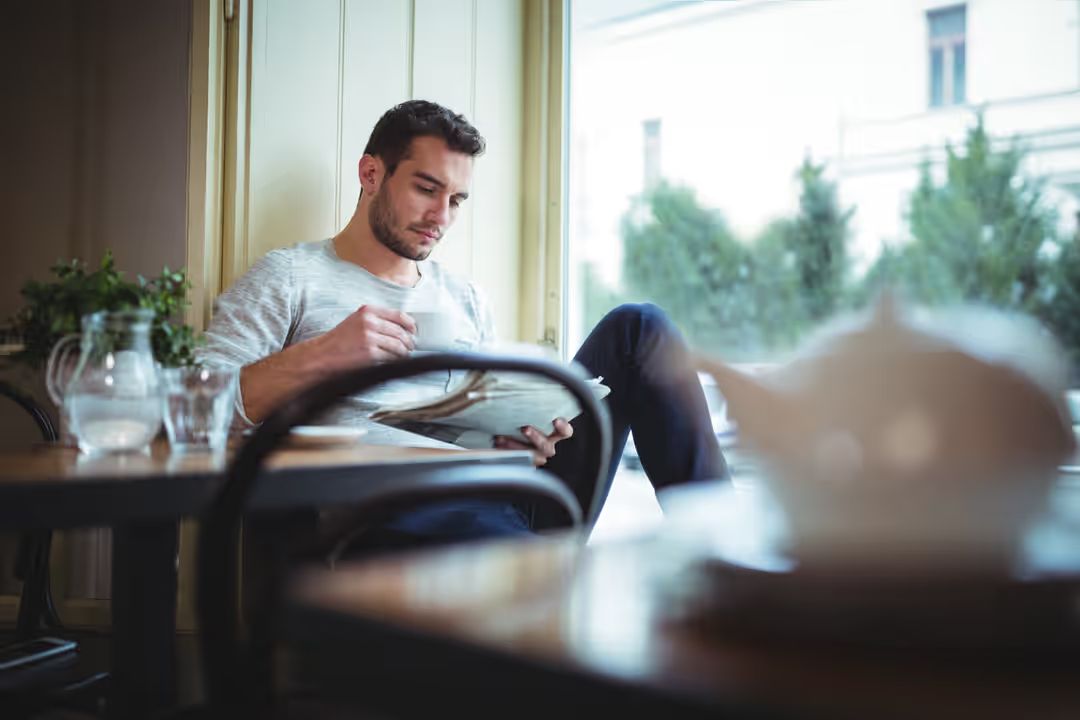 Photo of a man reading a newspaper and drinking coffee - Why you should keep track of industry trends - Image