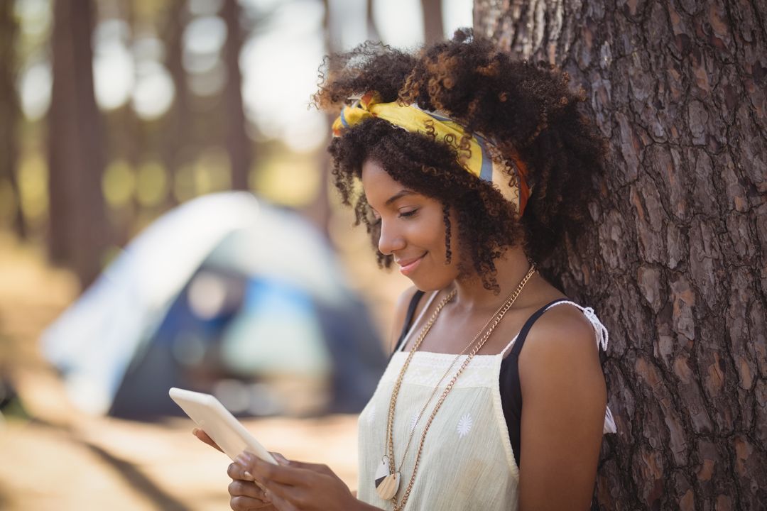 Image of a black woman with a yellow hairband being on her phone in the forest - Ten powerful advertising techniques to lure customers and boost your sales - Image