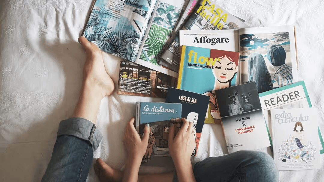 Woman sitting on a bed surrounded with print magazines ads - Retail marketing strategy tips and tricks to drive sales and save money - Image