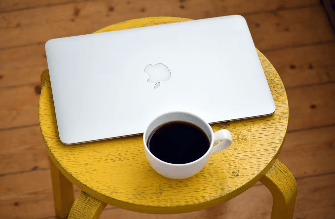 Overhead image of a Macbook on a yellow stool with coffee - Expert online marketing tips to improve your digital strategy and make more money - Image
