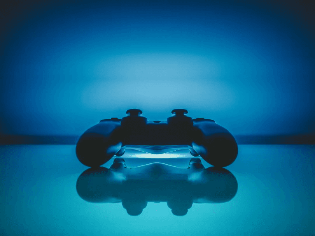 Lit Playstation controller placed on a reflective surface, blue hue from controller - 35 creative YouTube video ideas when you're out of inspiration - Image