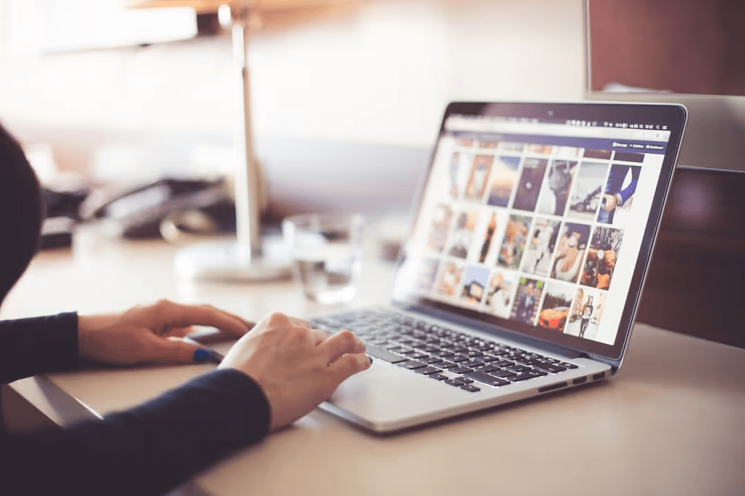 Person typing on a computer, on a desk, searching through a selection of images - What are the deciding factors when choosing between JPEG and PNG - Image