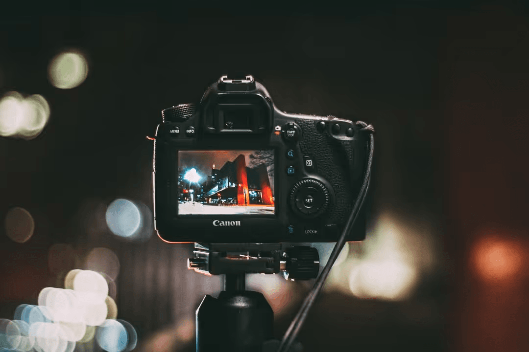 Canon camera on a tripod, taking a picture of a building at night with lights - PNG in professional photography - Image