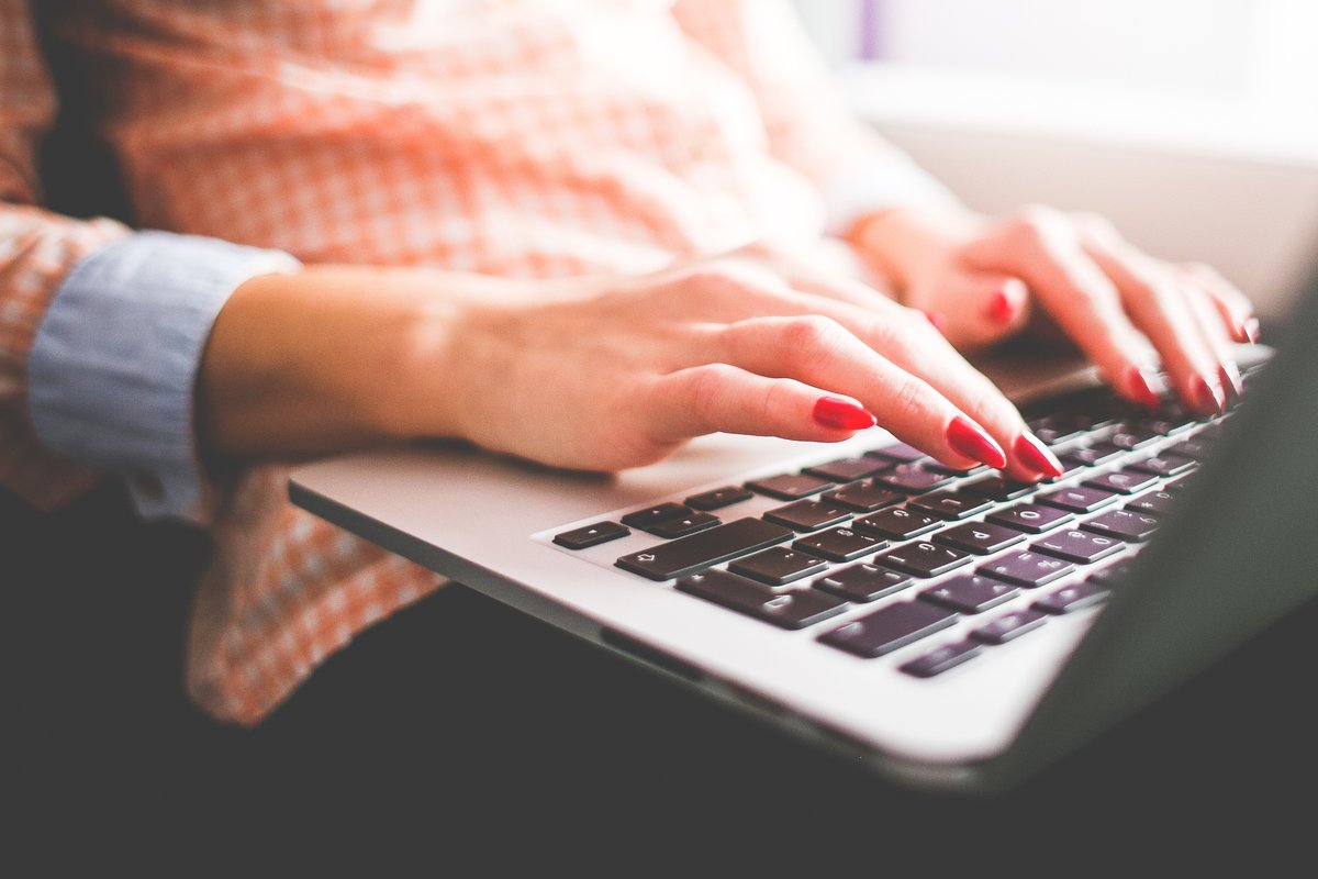 Low image of a woman with painted red nails typing on a laptop - How to choose the perfect YouTube thumbnail size - Image