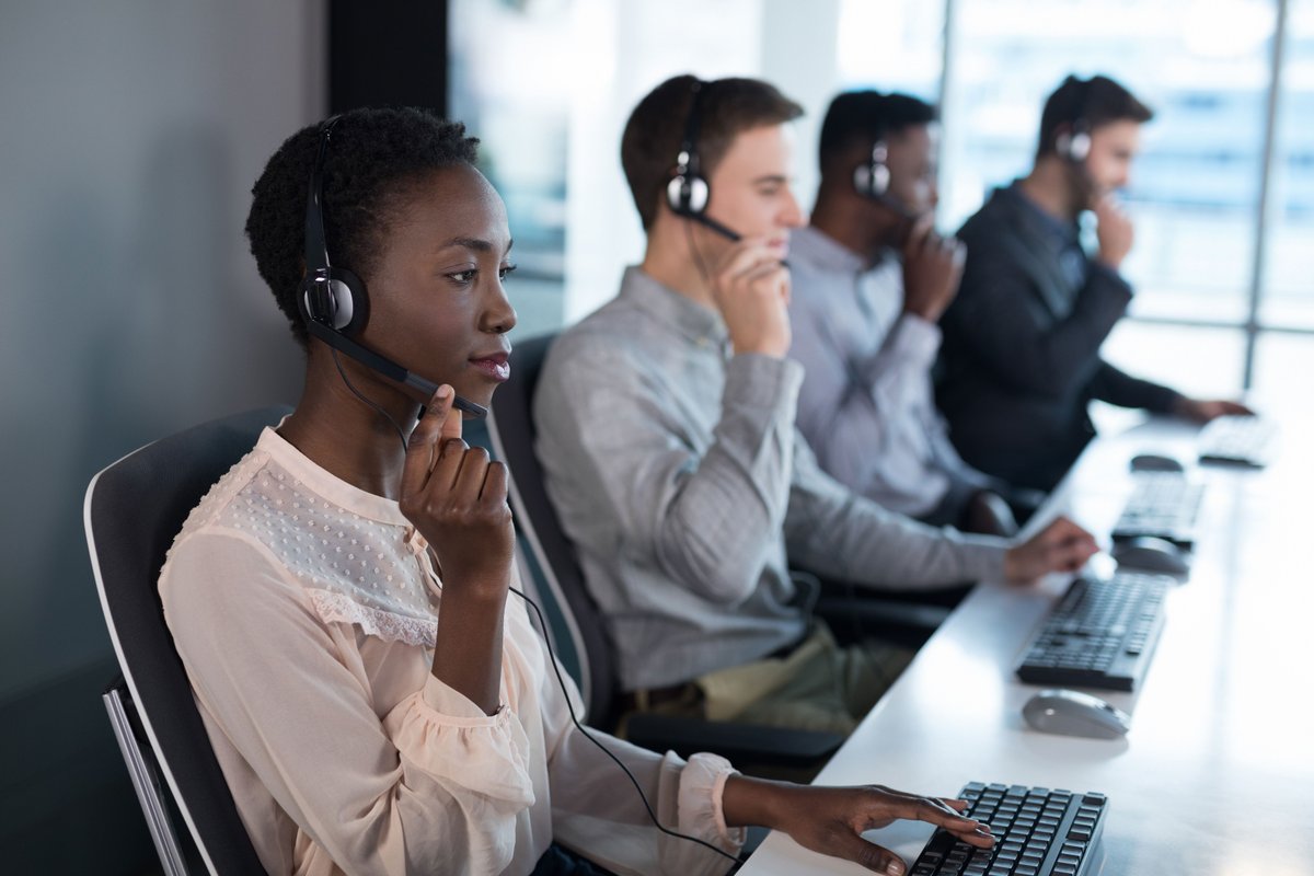 Image of four people working on computers with headsets on - Ten powerful advertising techniques to lure customers and boost your sales - Image