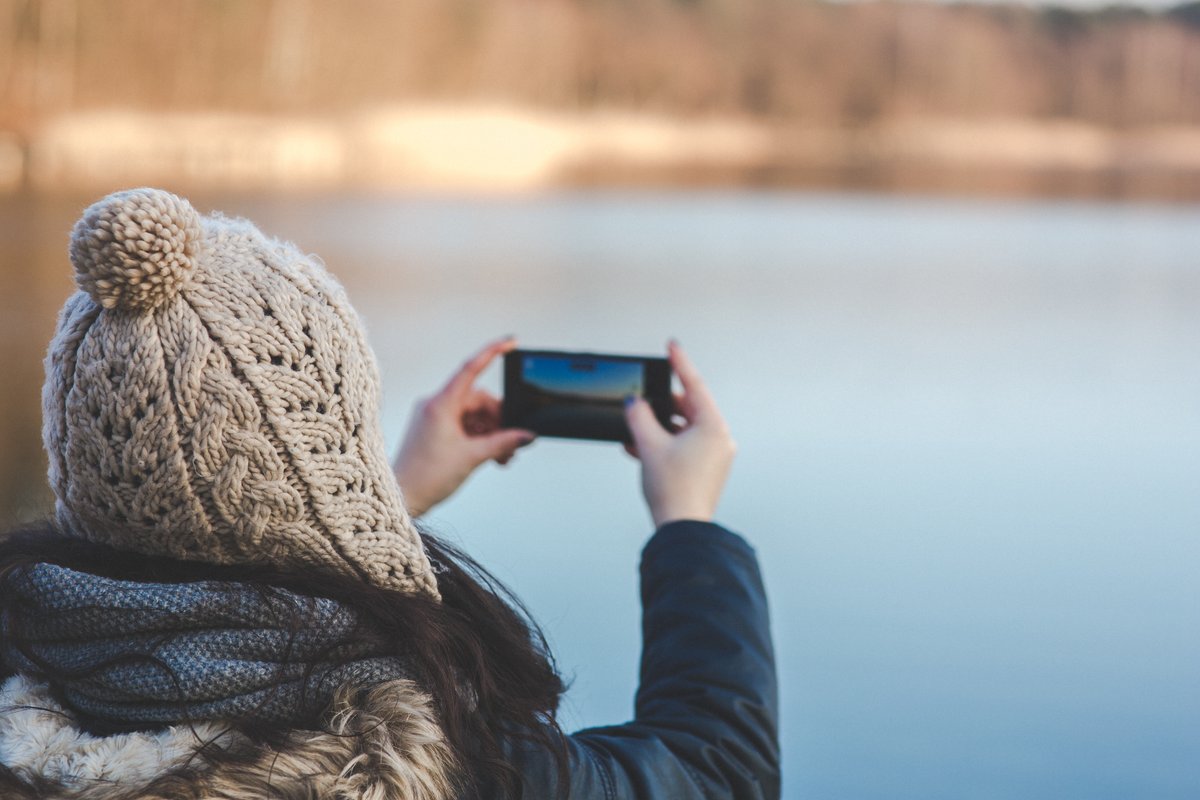 Image of a woman taking a picture of the view with her smartphone - A beginner's guide to royalty-free content - Image